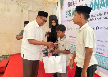 Plt Kadis Kominfo Aceh Besar Khairul Huda SKom MM, menyerahkan santuan kepada anak yatim dalam acara yang digelar SPS Aceh, di Gampong Doy, Kecamatan Ulee Kareng, Kota Banda Aceh, Kamis (20/3/2025) sore. FOTO/ MC ACEH BESAR