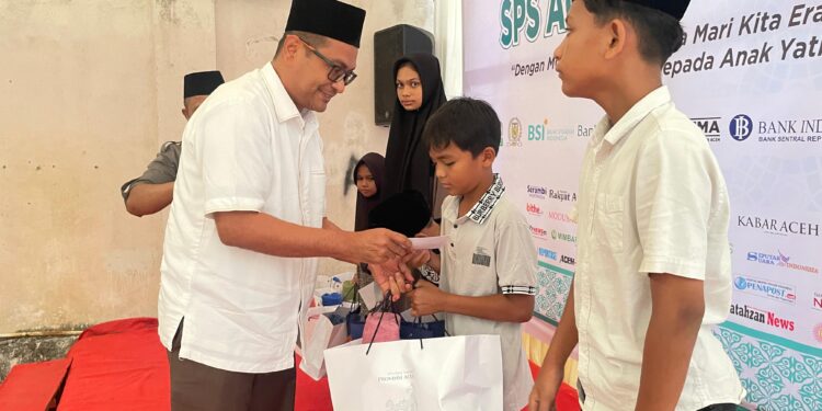 Plt Kadis Kominfo Aceh Besar Khairul Huda SKom MM menyerahkan santuan kepada anak yatim dalam acara yang digelar SPS Aceh di Gampong Doy Kecamatan Ulee Kareng Kota Banda Aceh Kamis 2032025 sore FOTO MC ACEH BESAR