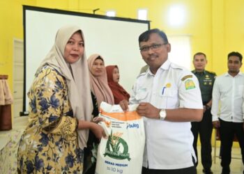 Kadis Pangan Aceh Besar Aliyadi SPi MM, menyerahkan bantuan beras BPB secara simbolis kepada seorang penerima manfaat, di Gedung UDKP Kecamatan Peukan Bada, Kabupaten Aceh Besar, Rabu (16/7/2025) pagi. FOTO/ MC ACEH BESAR