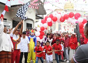Kadisparpora Aceh Besar Abdullah SSos mengangkat bendera pada Pelepasan Gerak Jalan Santai di halaman Kantor Keuchik Gampong Lubok Batee, Kecamatan Ingin, Aceh Besar, Minggu (10/08/2025). FOTO/MC ACEH BESAR