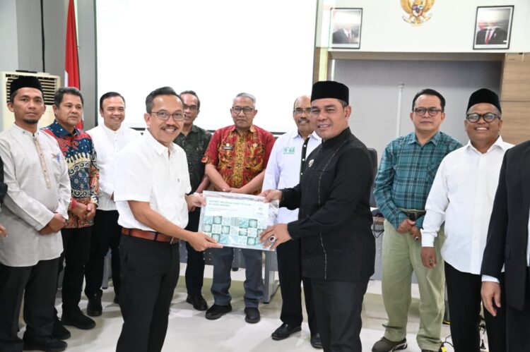 Bupati Aceh Besar H Syech Muharram Idris menerima dokumen Potret Wilayah Adat Mukim dari Kepala Badan Registrasi Wilayah Adat Kasmita Widodo pada acara menghadiri Kick off Meeting Riset Tenurial Subyek dan Objek Masyarakat Hukum Adat di Aula Balai Senak Lt 2 USK Darussalam Banda Aceh Jumat 22082025 FOTOMC ACEH BESAR