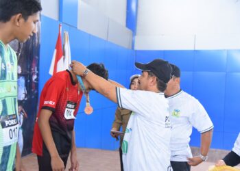 Wakil Bupati Aceh Besar Drs. H. Syukri A Jalil mengalungi medali dan menyerahkan piagam penghargaan kepada atlet olahraga atletik para peraih juara PORKAB Aceh Besar Tahun 2025 di Jantho Sport City (JSC), Selasa (9/9/2025). FOTO/MC ACEH BESAR
