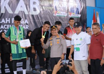Kapolres Aceh Besar AKBP Sujoko SIK MH, didampingi Kadisparpora Aceh Besar Abdullah SSos, menyerahkan medali Porkab Aceh Besar, kepada para juara cabor Atletik putra, di JSC Kota Jantho, Aceh Besar, Rabu (10/9/2025). FOTO/ PROKOPIM PEMKAB ACEH BESAR