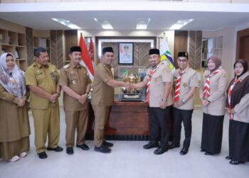 Bupati Aceh Besar H Muharram Idris didampingi Wabup Aceh Besar Drs H Syukri dan Sekdakab Aceh Besar Bahrul Jamil Ssos MSi menerima piala juara umum yang diraih Kwarcab Pramuka Aceh Besar pada Musabaqah Tunas Ramadhan ke-24 tahun 2025 dari Ketua Kwarcab Pramuka Aceh Besar Muhammad Iswanto SSTP MM di ruang kerja Bupati Aceh Besar, Selasa (23/9/2025). FOTO/ PROKOPIM PEMKAB ACEH BESAR