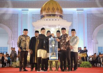 Bupati Aceh Besar H Muharram Idris (Syech Muharram) menerima piala bergilir juara umum MTQ ke-37 Aceh tahun 2025, dari Wakil Gubernur Aceh Fadhlullah SE, pada malam penutupan, di Arena Utama, Komplek Perkantoran Pemkab Pidie Jaya, Jumat (7/11/2025) malam. FOTO/ PROKOPIM PEMKAB ACEH BESAR
