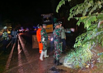 Petugas gabungan TNI, Polri, BPBD, dan relawan melakukan peninjauan serta pembersihan material longsor di ruas jalan Tapaktuan–Subulussalam, Desa Lhok Rukham, Aceh Selatan, Sabtu malam (22/11/2025).