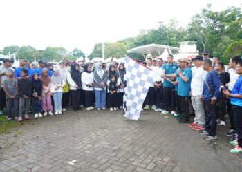 Wakil Bupati Aceh Besar Drs. H. Syukri A Jalil mengangkat bendera start saat menglepaskan peserta jalan sehat keluarga di lapangan Bungoeng jeumpa, Kota Jantho, Minggu (23/11/2025) pagi. FOTO/MC ACEH BESAR