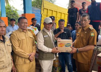 Bupati Aceh Besar H. Muharram Idris (Syech Muharram) menerima bantuan dari Camat Seulimuem Devi Satria, SE untuk korban banjir dan longsor yang melanda sejumlah kabupaten dan kota di Provinsi Aceh, di Gudang Logistik BPBD Aceh Besar, Kecamatan Sukamakmur, Senin (8/12/2025). FOTO/MC ACEH BESAR