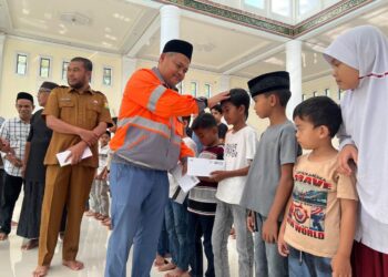 GA & Comrel Manager Solusi Bangun Andalas, Tafaul Rijal menyerahkan santunan anak yatim di Mesjid Kemukiman Kueh yang disaksikan oleh Asisten I Sekretaris Daerah (Sekda) Aceh Besar, Farhan AP dan tokoh masyarakat, 10 Maret 2026.