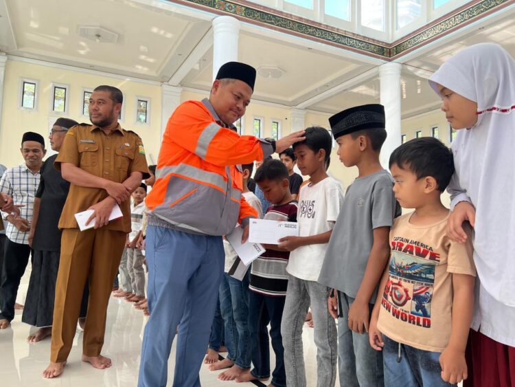 GA Comrel Manager Solusi Bangun Andalas Tafaul Rijal menyerahkan santunan anak yatim di Mesjid Kemukiman Kueh yang disaksikan oleh Asisten I Sekretaris Daerah Sekda Aceh Besar Farhan AP dan tokoh masyarakat 10 Maret 2026