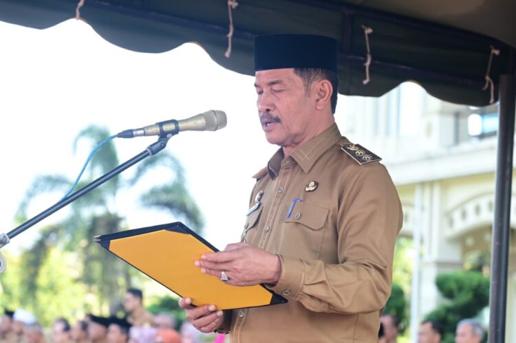 Wakil Bupati Aceh Besar Drs H Syukri bertindak selaku Pembina Apel Gabungan Organisasi Perangkat Daerah dalam rangka memperingati Hari Ulang Tahun Satuan Perlindungan Masyarakat Satlinmas ke 64 tahun 2026 di halaman Kantor Bupati Aceh Besar Senin 2042026 FOTO MC ACEH BESAR