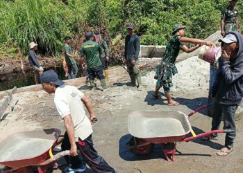 Personel TNI dari Kodim 0107/Aceh Selatan bersama masyarakat Desa Raket bergotong royong mempercepat pembangunan jembatan Aramco di Kecamatan Trumon, Kabupaten Aceh Selatan, Rabu (22/4/2026).