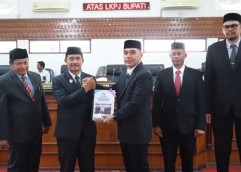 Wakil Bupati Aceh Besar, Drs. Syukri, menyerahkan dokumen tanggapan pemerintah daerah atas rekomendasi DPRK terhadap LKPJ Tahun Anggaran 2025 kepada Ketua DPRK dalam rapat paripurna di Gedung DPRK Aceh Besar, Kota Jantho, Senin (27/4/2026). FOTO/MC ACEH BESAR