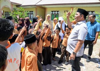 Bupati Aceh Besar, H Muharram Idris berbincang akrab dengan murid saat berkunjung di SDN Limpok, Darussalam, Aceh Besar, Jumat (08/05/2026). FOTO/MC ACEH BESAR