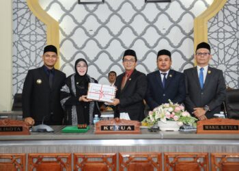Wali Kota Banda Aceh, Illiza Sa’aduddin Djamal, saat menyerahkan Laporan Keterangan Pertanggungjawaban (LKPJ) Tahun Anggaran 2025 kepada DPRK Banda Aceh kepada Ketua DPRK Banda Aceh, Irwansyah ST, didampingi Wakil Ketua I Daniel Abdul Wahab, S.Pd., dan Wakil Ketua II, Dr. Musriadi Aswad, S.Pd., M.Pd dalam rapat paripurna di Gedung DPRK Banda Aceh, Senin (13/7/2026). FOTO: Humas DPRK Banda Aceh.