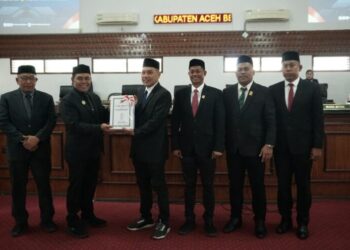 Bupati Aceh Besar H Muharram Idris (Syech Muharram), menyerahkan Pengantar Nota Keuangan dan Rancangan Qanun tentang P-APBK Aceh Besar Tahun Anggaran 2026 kepada Ketua DPRK Aceh Besar Abdul Muchti SIKom, dalam rapat paripurna di Aula Rapat Gedung DPRK Aceh Besar, Kota Jantho, Kamis (24/9/2026). FOTO/ MC ACEH BESAR