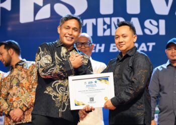 Sekda Aceh Barat, Dr. Ir. Kurdi, ST, MT, MH, IPM, ASEAN-Eng, menyerahkan penghargaan kepada Sekjen SMSI Aceh Barat, Riosa, sebagai Organisasi Media Pegiat Literasi Kabupaten Aceh Barat Tahun 2026, pada malam penutupan Festival Literasi Aceh Barat 2026, Sabtu (26/9/2026). Foto: (SMSI Aceh Barat).