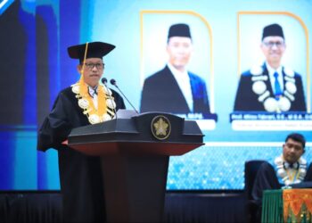Rektor USK Prof. Mirza Tabrani, S.E., M.B.A., D.B.A., menyampaikan orasi ilmiah pada peringatan Milad ke-65 USK di Gedung AAC Dayan Dawood, Banda Aceh, Senin (12/10/2026). Foto: (Humas USK)