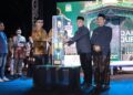 Bupati Aceh Besar H Muharram Idris menyerahkan piala bergilir kepada Camat Peukan Bada Salamuddin ZM SE usai menjadi Juara Umum MTQ ke 35 Tingkat Kabupaten Aceh Besar pada malam penutupan di arena utama Lapangan Kemukiman Bung Cala Kecamatan Kuta Baro Jumat 30102026 malam FOTOPROKOPIM ACEH BESAR