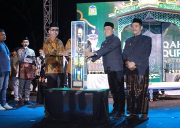Bupati Aceh Besar H. Muharram Idris menyerahkan piala bergilir kepada Camat Peukan Bada, Salamuddin ZM, SE usai menjadi Juara Umum MTQ ke-35 Tingkat Kabupaten Aceh Besar pada malam penutupan di arena utama, Lapangan Kemukiman Bung Cala, Kecamatan Kuta Baro, Jumat (30/10/2026) malam. FOTO/PROKOPIM ACEH BESAR