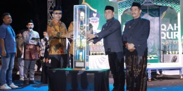 Bupati Aceh Besar H Muharram Idris menyerahkan piala bergilir kepada Camat Peukan Bada Salamuddin ZM SE usai menjadi Juara Umum MTQ ke 35 Tingkat Kabupaten Aceh Besar pada malam penutupan di arena utama Lapangan Kemukiman Bung Cala Kecamatan Kuta Baro Jumat 30102026 malam FOTOPROKOPIM ACEH BESAR